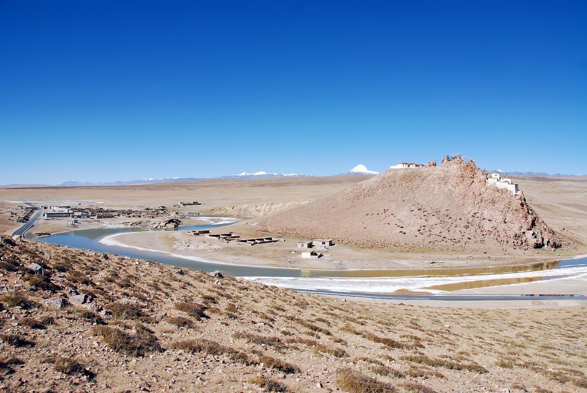 32 Chiu Village Next To Ganga Chu With Chiu Gompa On Hill And Mount Kailash Behind Chiu Village sits next to Ganga Chu, the water channel that runs from Lake Manasarovar to Rakshas Tal. When water flows through this channel, it is said to auger well for the Tibetan people. Chiu Gompa (4639m) perched on a hill with Mount Kailash behind completes the view.